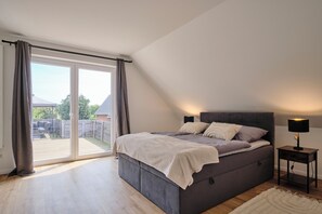 A bedroom with a bed, a nightstand, and a view of the backyard through a sliding door. - "12 Monkeys" Vacation Rental—No Parties Allowed! (Stuhr)