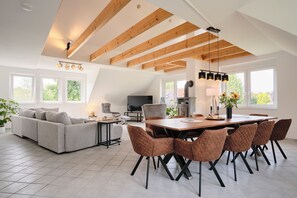 Amplia sala de estar con un sofá grande, una mesa de comedor con sillas, un televisor y una chimenea.