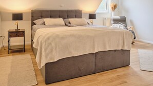 Une chambre à coucher moderne avec un grand lit, une table de chevet, une lampe et une fenêtre donnant sur un beau paysage.