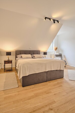 A modern bedroom with a large bed, a bedside table, a lamp, and a window with a view. - "12 Monkeys" Vacation Rental—No Parties Allowed! (Stuhr)