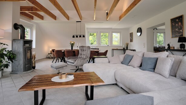 Un salon moderne avec un plafond en bois, une cheminée, un canapé et un coin repas.