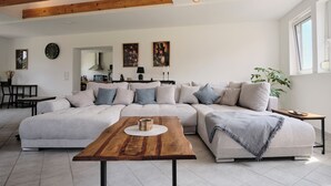 A modern living room with a sectional sofa, a wooden coffee table, and a dining area with a table and chairs. - "12 Monkeys" Vacation Rental—No Parties Allowed! (Stuhr)