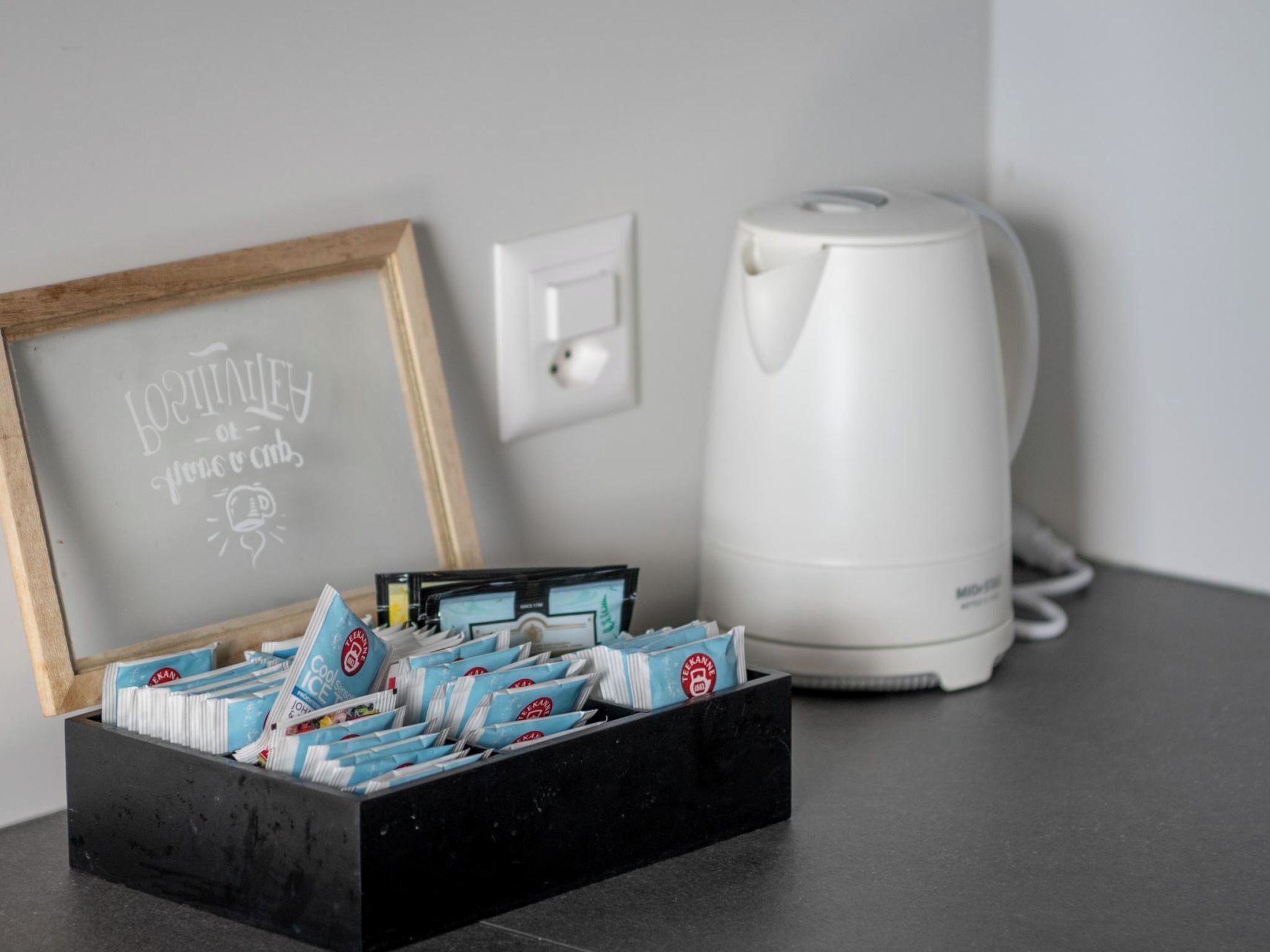A coffee maker and a framed sign with text on a countertop.