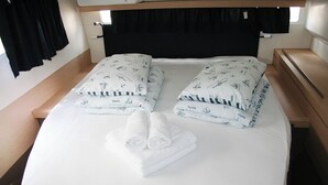 A neatly made bed with white linens and towels, a wooden headboard, and a small bedside table with a lamp. - Sun-kissed Sailing Adventure in Split-Dalmatia, Croatia (Seget Donji)