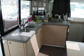 A compact kitchen with a sink, a stove, and a window overlooking a parking area.