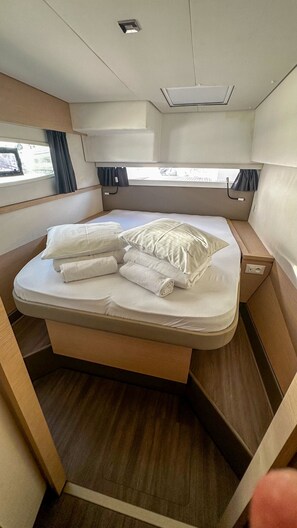 A compact bed with a headboard, a bedside table, and a window with curtains. - Sun-Kissed Sailing Adventure in Sibenik, Croatia (Primošten)