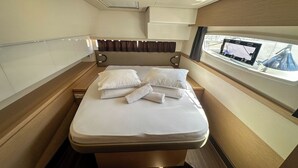 Una cabina compatta e ben illuminata con un letto singolo, una finestra vista e un pannello di controllo sulla destra.