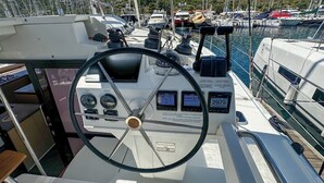 Postazione di guida di una barca con diversi strumenti di controllo, un timone e un display di navigazione.