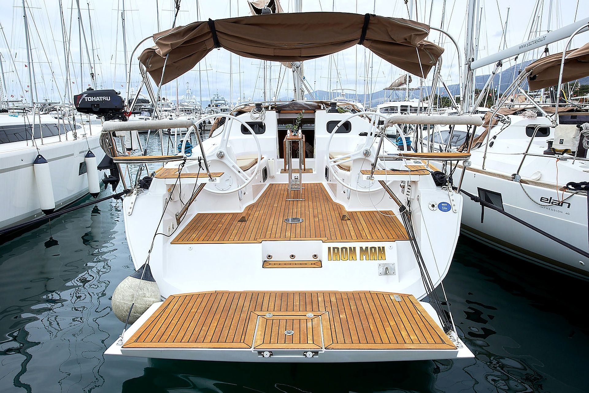 A yacht with a wooden deck, a nameplate reading 'IRON MAN,' and a cabin with a window.