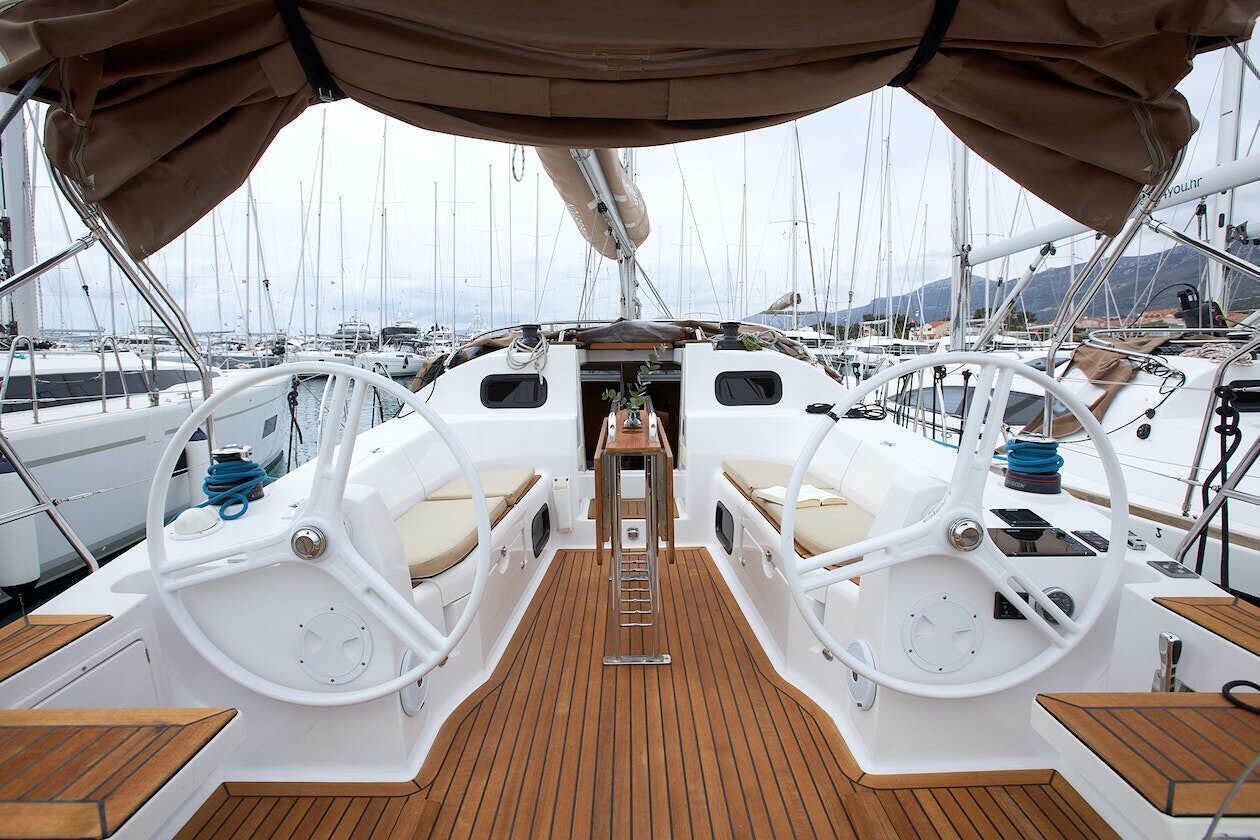 A boat deck with two steering wheels, a central ladder, and a covered area.