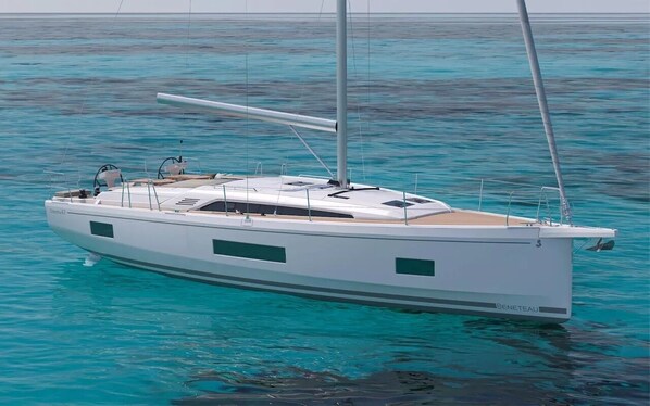 Eine weiße Segelyacht mit Kabine und zwei Masten, die auf türkisfarbenem Wasser treibt.