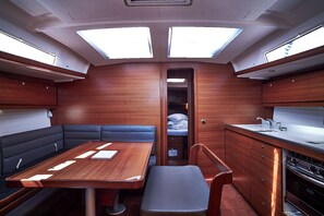 A compact kitchen with a dining area, a small sleeping berth, and a window for natural light.