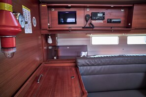 A compact RV interior with a wooden finish, a mounted television, a radio, and a small window.