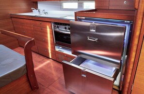 Eine kleine Küche mit einem Edelstahlkühlschrank, einer Spüle und Holzschränken.