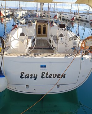 Ein Boot namens 'Easy Eleven' liegt in einer Marina mit anderen Booten, einem Holzboden und einer Kabine mit einem Fenster.