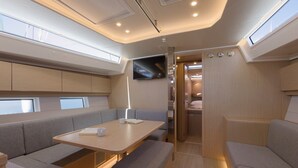 A modern interior with a sofa, table, and a TV mounted on the wall. - Sun-Kissed Sailing Adventure in Split, Croatia (Kaštel Gomilica)