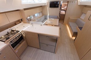 A compact kitchen with a stove, sink, and storage cabinets. - Sun-Kissed Sailing Adventure in Split, Croatia (Kaštel Gomilica)