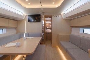 A compact, modern interior with a dining area, seating, a TV, and a visible closet. - Sun-Kissed Sailing Adventure in Split, Croatia (Kaštel Gomilica)