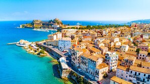 Une ville côtière dotée de bâtiments historiques, d’un port de plaisance et d’un fort surplombant la mer.