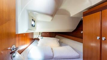 Une petite cabine comprenant un lit, des meubles en bois et une petite fenêtre.