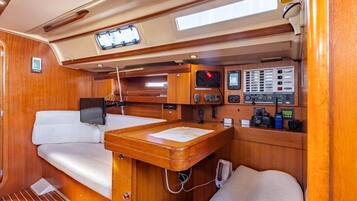Un intérieur compact doté d’une cabine en bois, d’un petit panneau de commande, d’une zone de sièges rembourrés et d’une fenêtre.