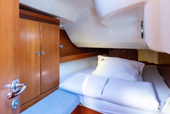 A compact cabin with a bed, a wooden wardrobe, and a small bench.