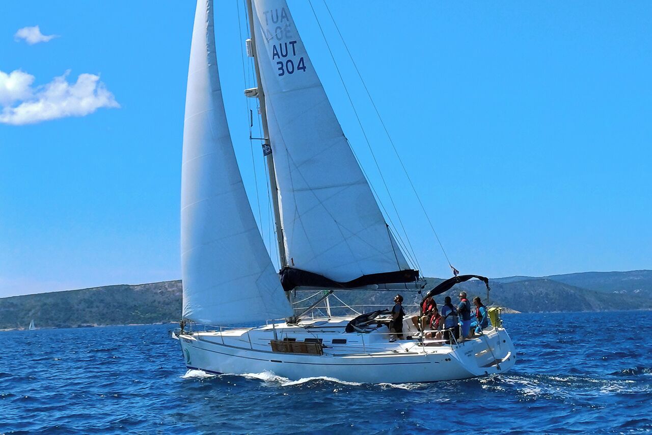 Un velero con pasajeros navegando en aguas azules, en un día despejado.