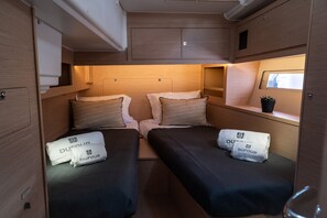 Ein kompaktes Wohnmobil-Interieur mit zwei Betten, einem kleinen Fenster und einem Blumentopf.