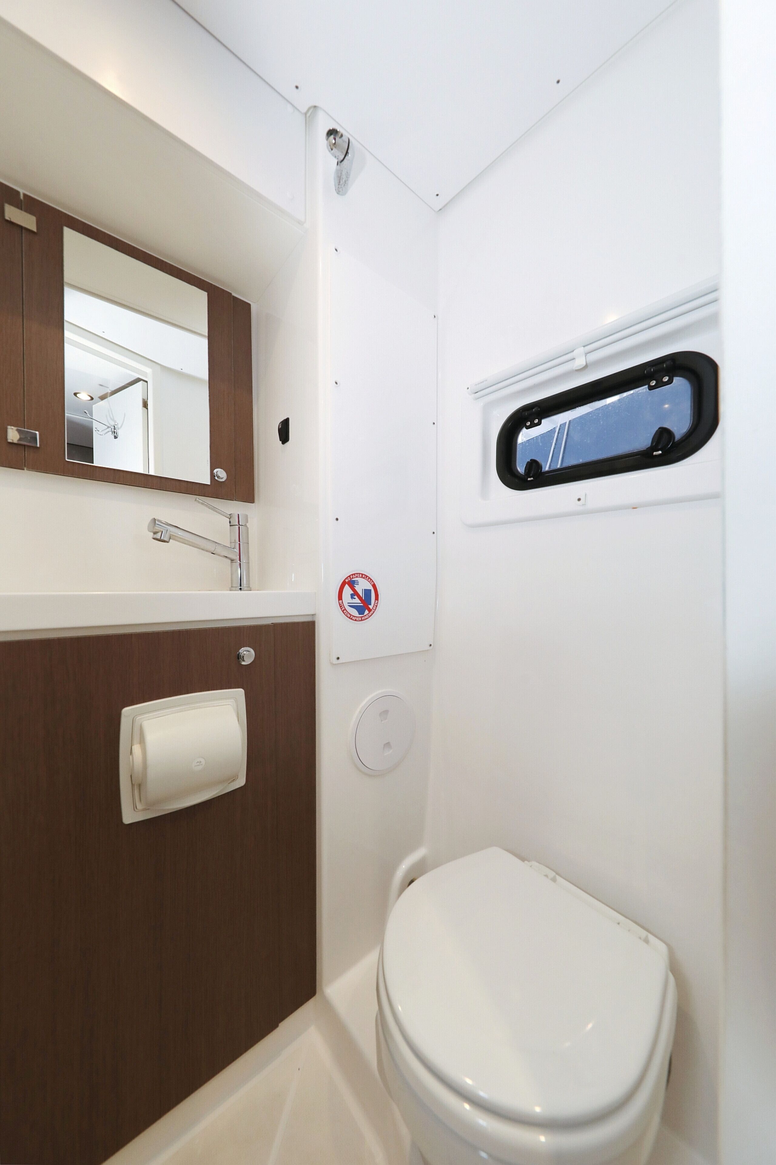 A compact bathroom with a toilet, a sink, a mirror, and a window.