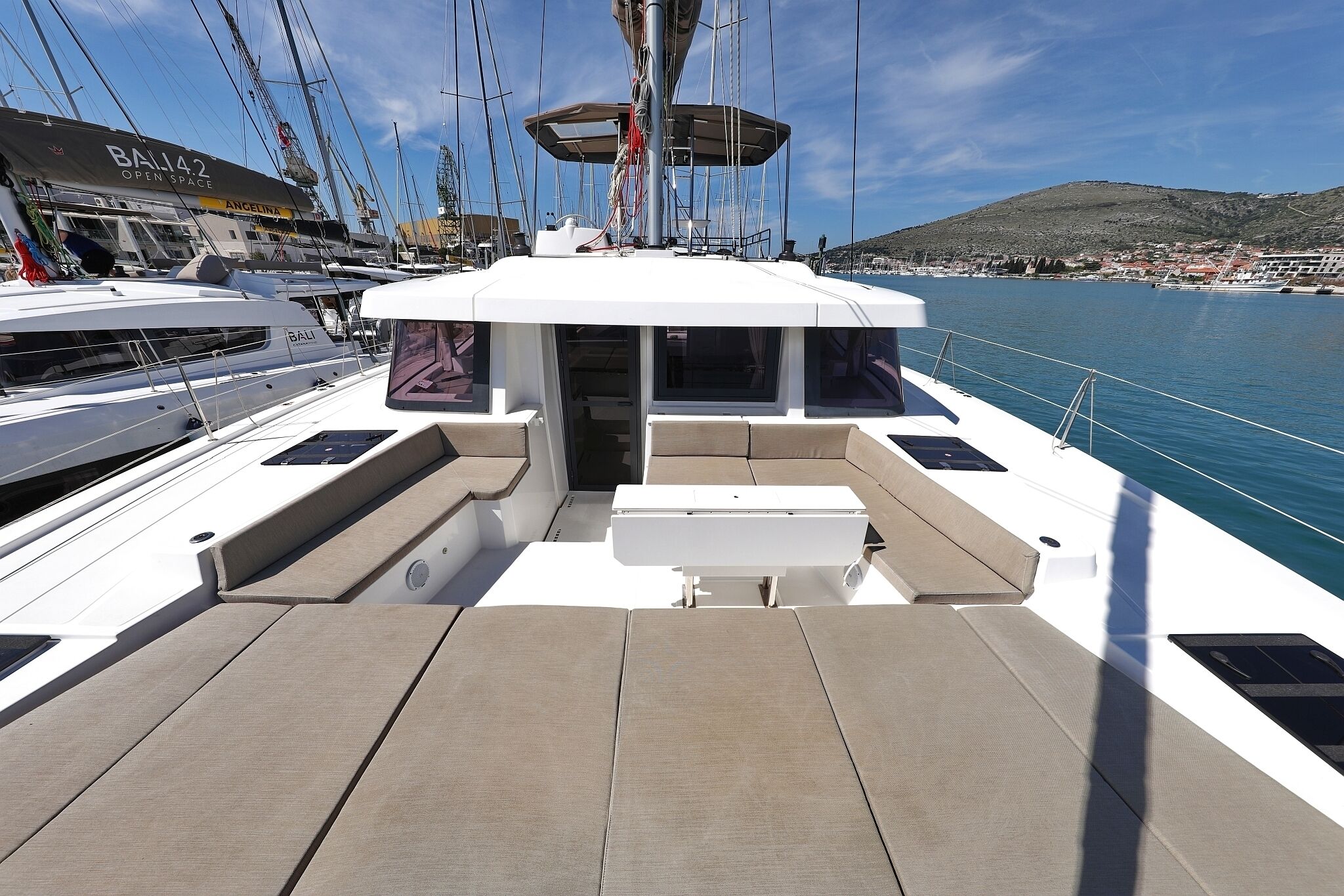 A boat deck with seating, a mast, and a marina in the background.
