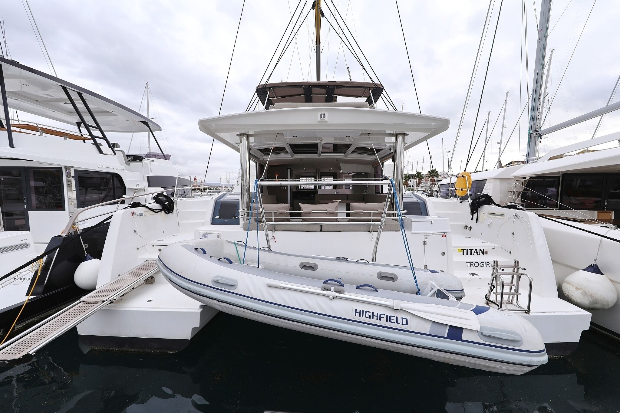 A yacht docked at a marina with a covered deck area, a seating arrangement, and a lifebuoy.