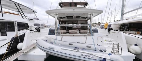 A yacht docked at a marina with a covered deck area, a seating arrangement, and a lifebuoy.