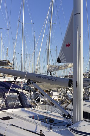 Un puerto deportivo con varios veleros amarrados, destacando una vela con una dirección web y un logotipo de hoja de arce roja.