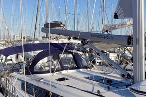 A marina with multiple sailboats docked, some with canopies, and a website address on one boat. - Sun-Kissed Sailing Adventure in Split, Croatia (Kaštel Gomilica)