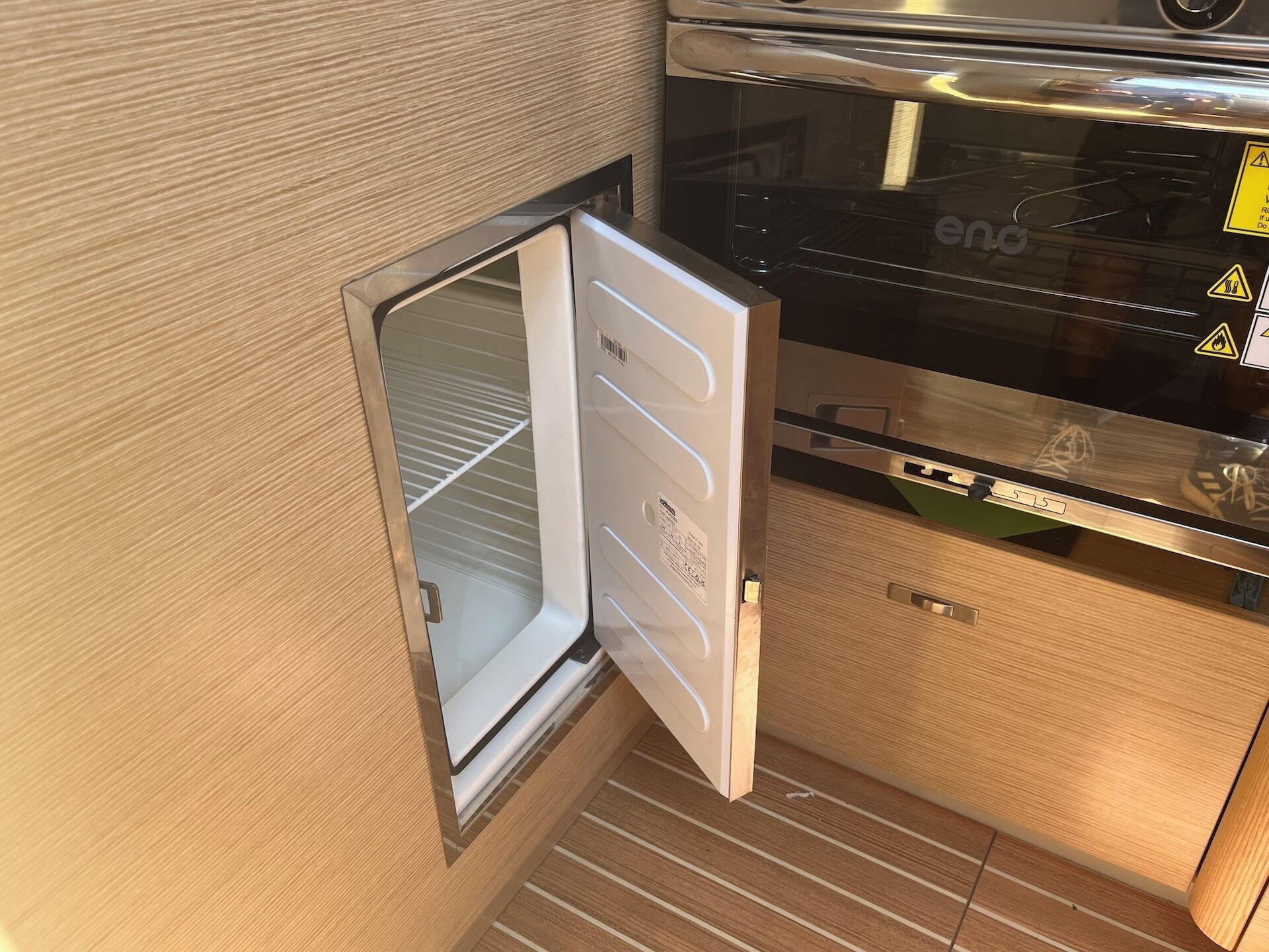 Una cocina compacta con microondas integrado, un refrigerador pequeño y una encimera de madera.