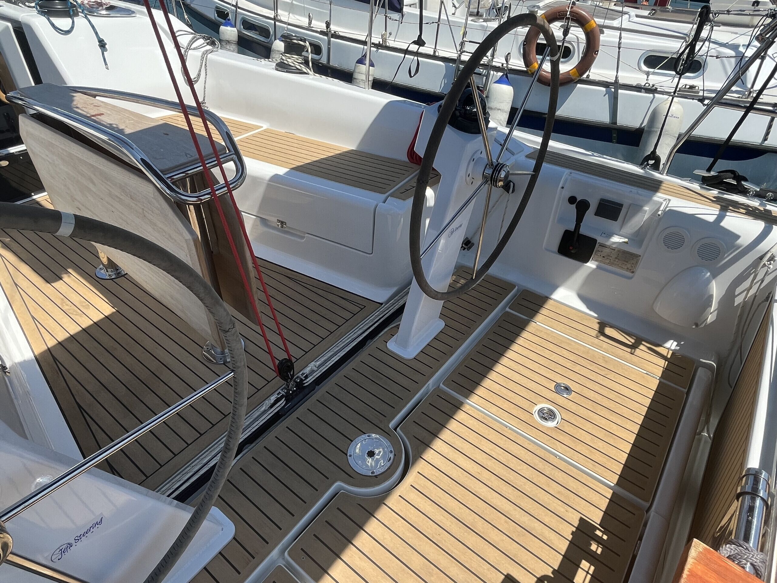 Cubierta de barco con timón, anillo salvavidas y panel de control.
