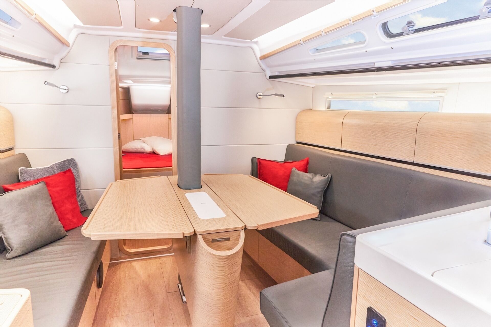A compact interior with a wooden table, cushioned seating, and a small bed.