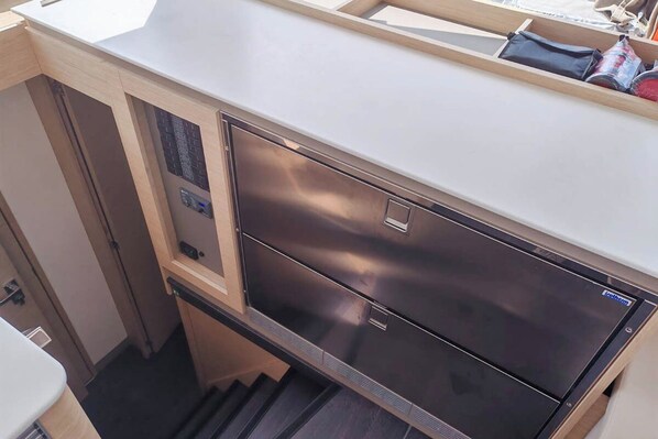 Eine kleine Küche mit einem Edelstahl-Kühlschrank, einem eingebauten Ofen und einer Arbeitsplatte.