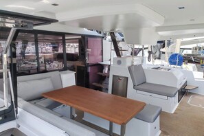 A boat interior with a wooden table, cushioned seating, and a window overlooking the water. - Sun-kissed Sailing Adventure in Split-Dalmatia, Croatia (Seget Donji)