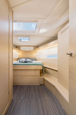 Un intérieur compact et bien éclairé, avec un lit superposé, des fenêtres de toit et un petit espace bureau.