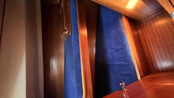 A narrow, enclosed space with wooden paneling and blue curtains.