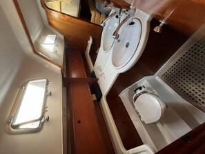 Une petite salle de bain avec un meuble-lavabo en bois, deux vasques, un miroir et des toilettes.