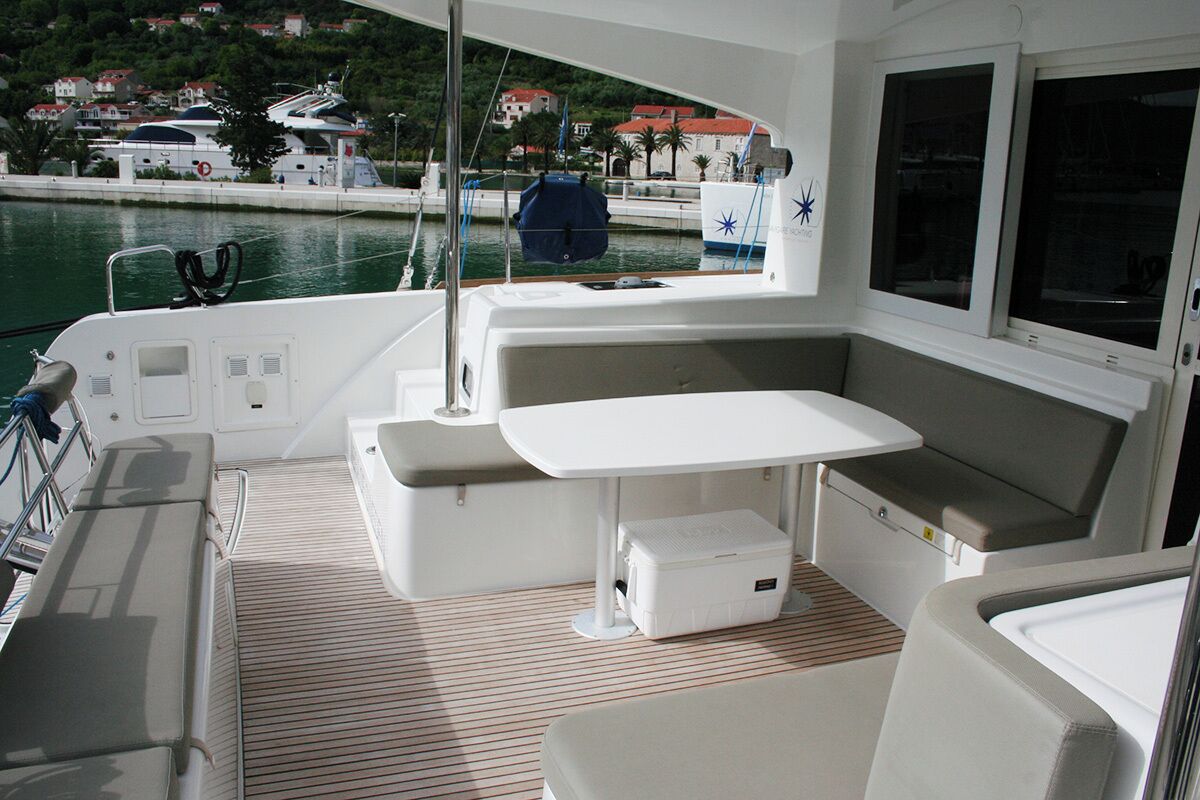 A boat's interior with a table, seating, and a view of the marina.