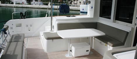A boat's interior with a table, seating, and a view of the marina.