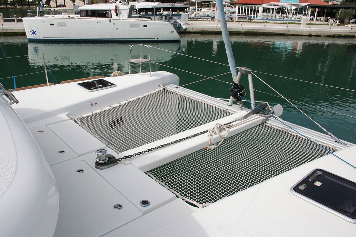 Cubierta de barco con una zona resguardada por una red, un cabrestante y una pequeña cabina con ventana.