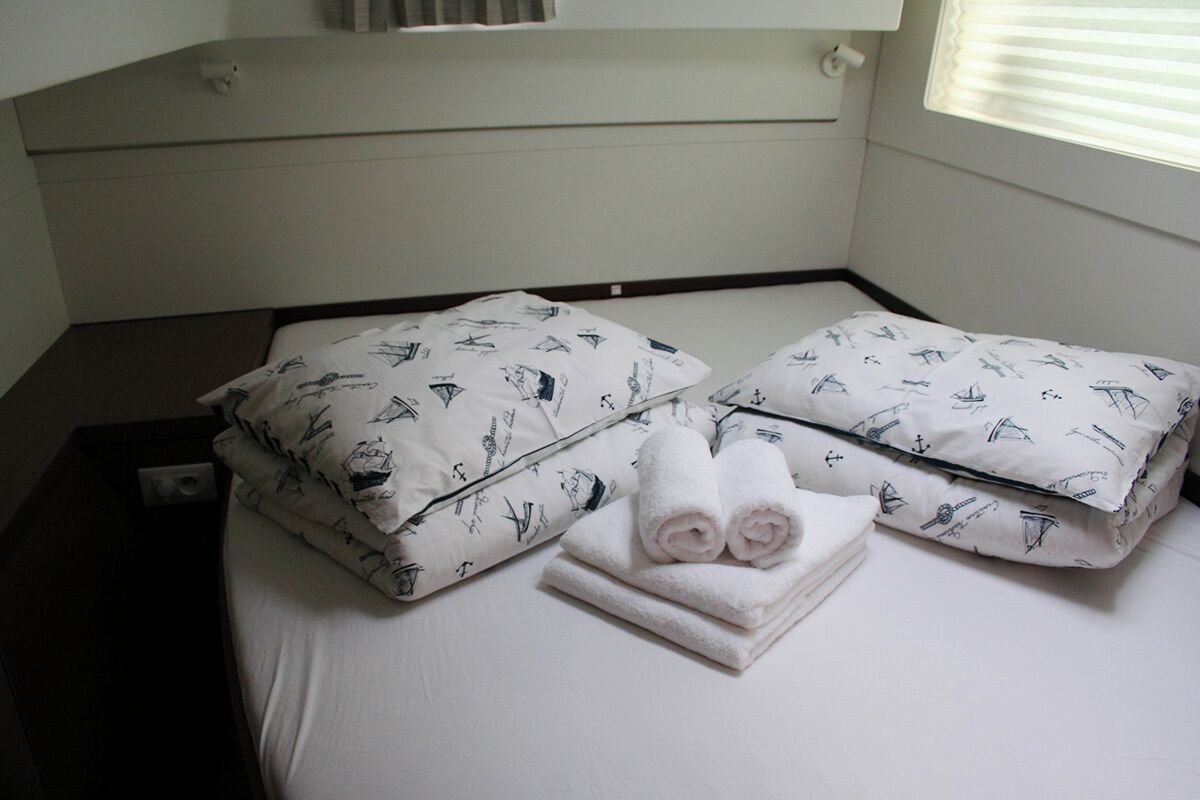 A hotel room with a bed, pillows, and a neatly folded towel.