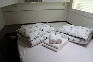 Ein Hotelzimmer mit einem Bett, Kissen und einem ordentlich gefalteten Handtuch.