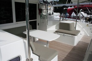 Ein Bootsdeck mit Tisch, gepolsterten Sitzgelegenheiten und einem kleinen Fenster.