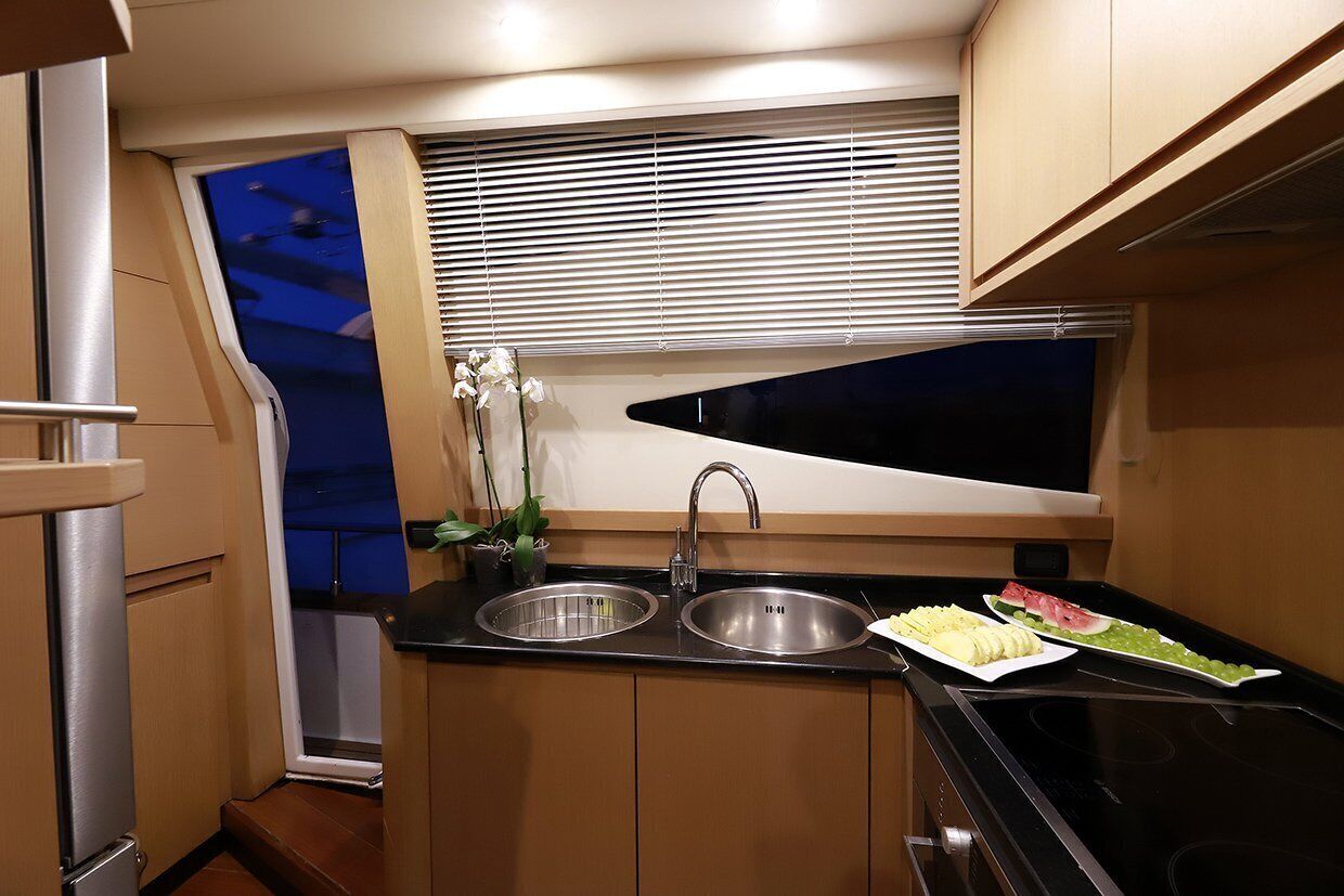 A compact kitchen with a sink, stove, and window blinds.