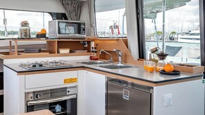 Uma cozinha compacta tipo corredor, equipada com micro-ondas, fogão, pia e mini-geladeira.